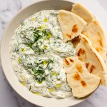 Vegan tzatziki in a bowl with pita on the side of the bowl